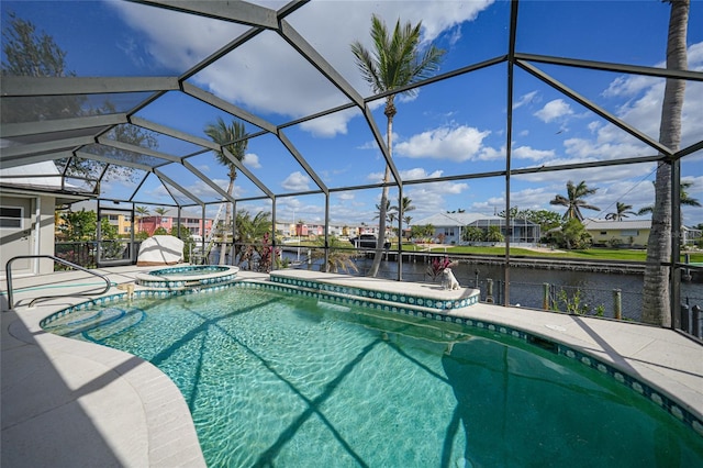 view of pool with glass enclosure, a patio area, a water view, and an in ground hot tub