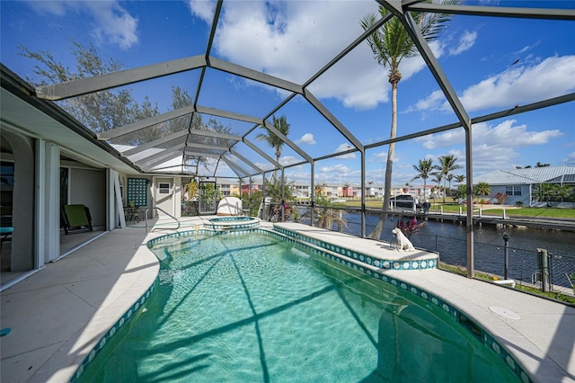 view of pool with glass enclosure, a patio area, a water view, and an in ground hot tub