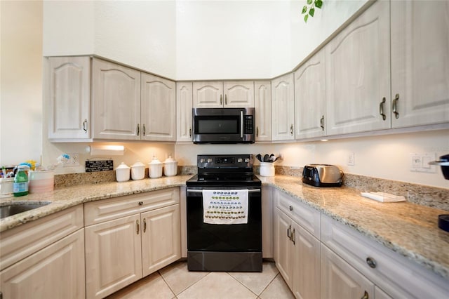 kitchen with light tile patterned flooring, light stone counters, sink, and black / electric stove