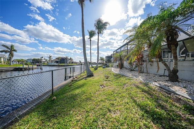 dock area featuring a lawn, glass enclosure, and a water view