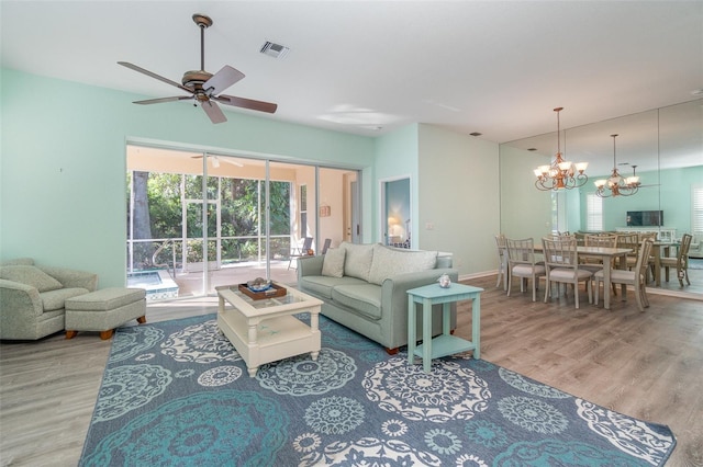 living room with hardwood / wood-style floors and ceiling fan with notable chandelier