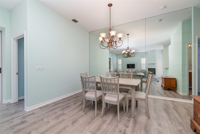 10494 Princess Ct, Punta Gorda, FL 33955 - dining room featuring a chandelier, light wood-style flooring, and a fireplace