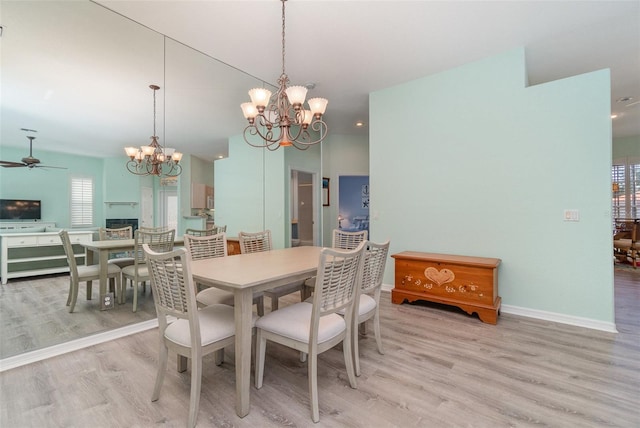 dining area with ceiling fan with notable chandelier and light hardwood / wood-style floors