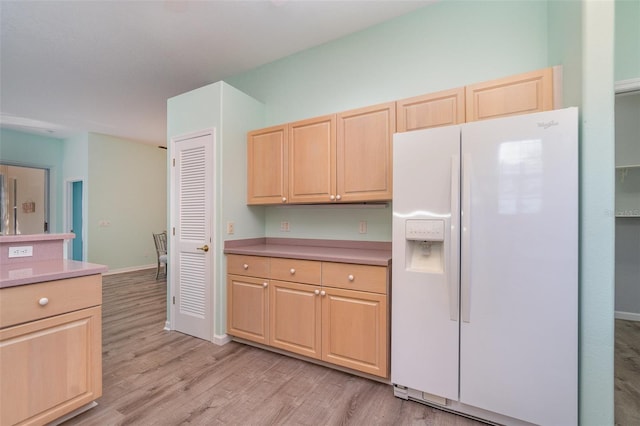 kitchen featuring white refrigerator with ice dispenser, light brown cabinetry, and light hardwood / wood-style floors