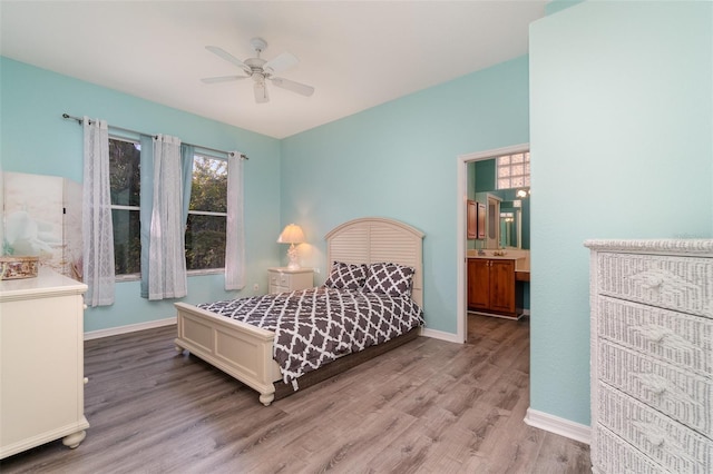 bedroom with ensuite bathroom, light hardwood / wood-style flooring, and ceiling fan