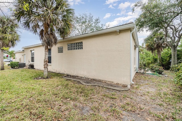 view of side of home with central AC unit and a yard