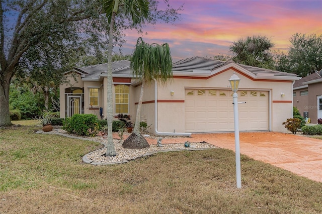 single story home featuring a lawn and a garage