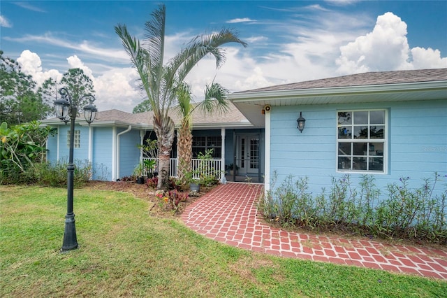 ranch-style home featuring covered porch and a front lawn