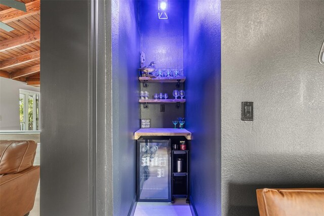 bar with lofted ceiling with beams, wood ceiling, and beverage cooler