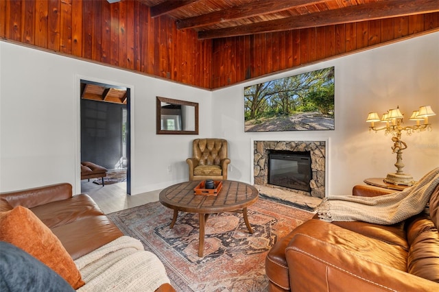 living room with beam ceiling, a stone fireplace, wooden ceiling, and light hardwood / wood-style floors