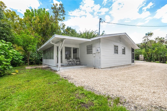 rear view of property featuring covered porch and a yard