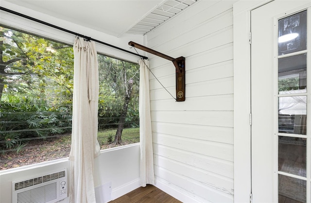 entryway with a wall mounted AC, wooden walls, plenty of natural light, and dark wood-type flooring