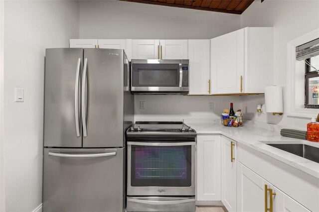 kitchen featuring light stone counters, white cabinets, stainless steel appliances, and wooden ceiling