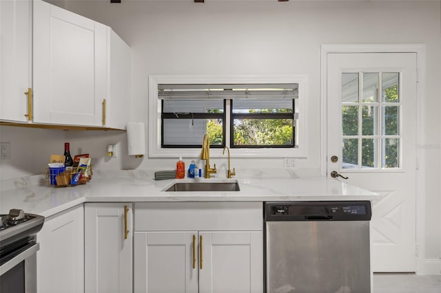 kitchen with light stone counters, white cabinetry, sink, and appliances with stainless steel finishes