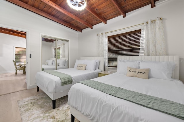 bedroom featuring a closet, beamed ceiling, wooden ceiling, and light hardwood / wood-style floors