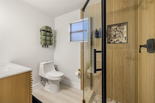 bathroom with wood-type flooring, vanity, toilet, and a shower with shower door