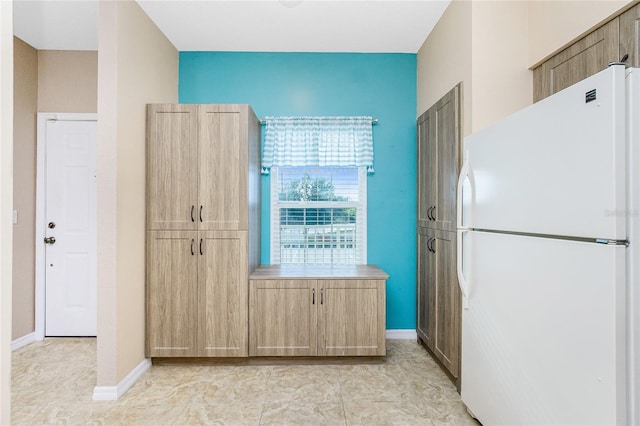 kitchen featuring white refrigerator and light brown cabinetry