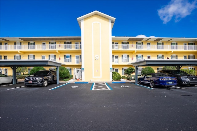 view of property featuring covered and uncovered parking