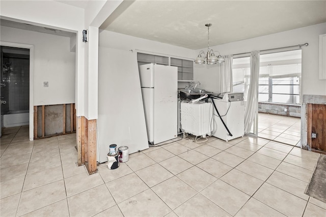 unfurnished dining area with light tile patterned flooring, washer / dryer, sink, and a chandelier