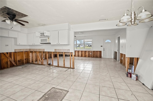 kitchen with ceiling fan with notable chandelier, white cabinetry, a textured ceiling, and light tile patterned floors