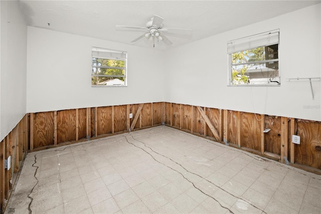 spare room with a wealth of natural light, wooden walls, and ceiling fan