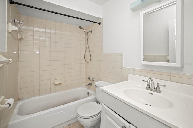 full bathroom featuring tiled shower / bath combo, toilet, tile walls, and vanity