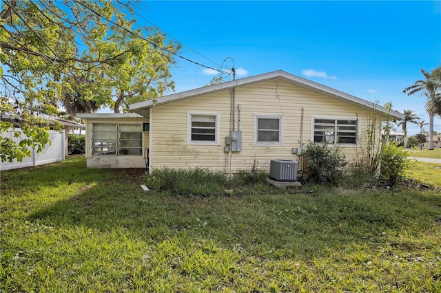 back of property featuring a sunroom, central AC, and a lawn