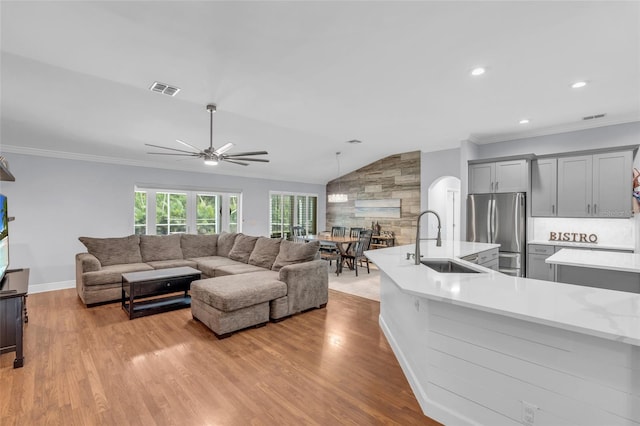 living room featuring ornamental molding, ceiling fan, sink, light hardwood / wood-style flooring, and lofted ceiling