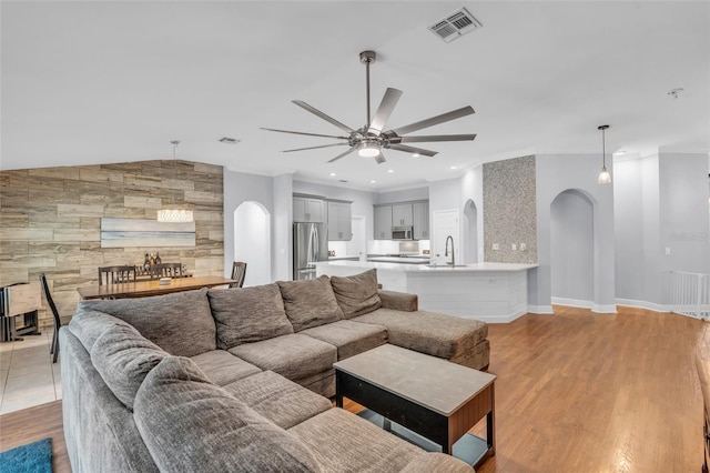 living room featuring ceiling fan, sink, light wood-type flooring, and ornamental molding