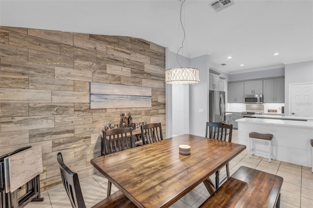 tiled dining area with ornamental molding, vaulted ceiling, and an inviting chandelier