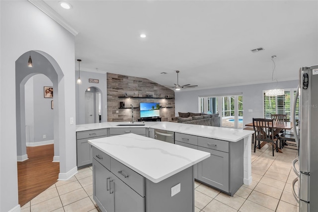 kitchen with stainless steel appliances, ceiling fan, light tile patterned floors, decorative light fixtures, and a kitchen island