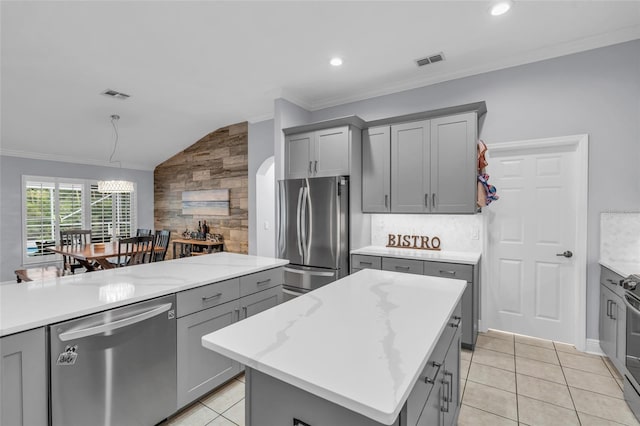 kitchen featuring a kitchen island, lofted ceiling, gray cabinets, light tile patterned floors, and appliances with stainless steel finishes