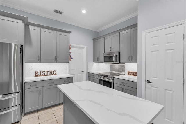 kitchen featuring tasteful backsplash, gray cabinets, stainless steel appliances, and ornamental molding