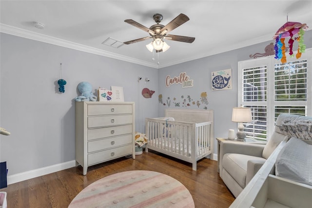 bedroom with ceiling fan, dark hardwood / wood-style flooring, a nursery area, and ornamental molding