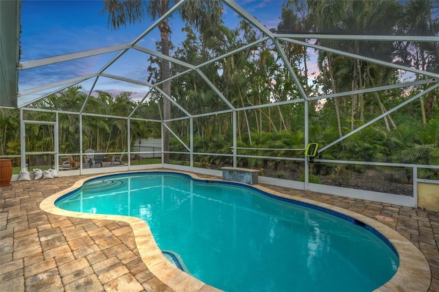 pool at dusk with a lanai and a patio area