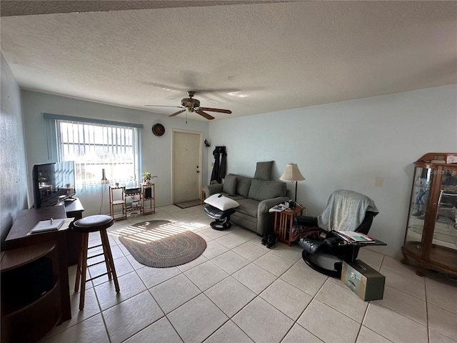 living room with ceiling fan, light tile patterned floors, and a textured ceiling