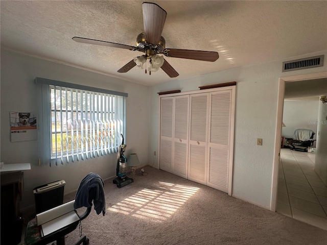 office space featuring ceiling fan, light colored carpet, and a textured ceiling