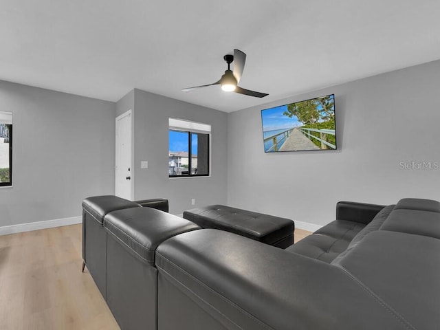 cinema room featuring plenty of natural light, a ceiling fan, baseboards, and light wood finished floors