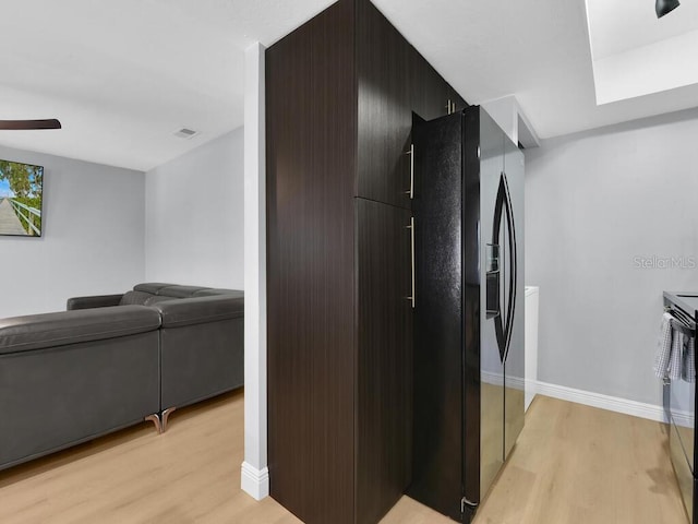 kitchen with electric range, light hardwood / wood-style floors, black fridge, and ceiling fan