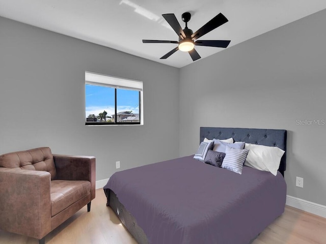 bedroom with light wood-style flooring, a ceiling fan, and baseboards