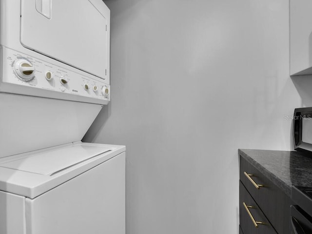 washroom featuring stacked washer / dryer and cabinet space