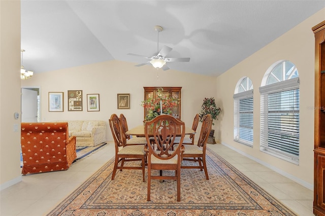 tiled dining room with ceiling fan with notable chandelier and vaulted ceiling