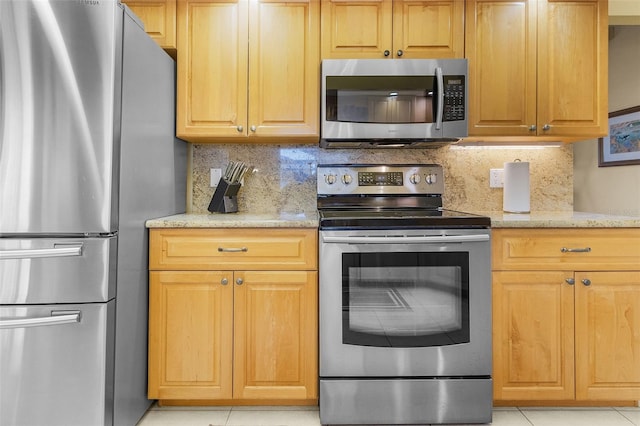 kitchen featuring backsplash, light stone countertops, light tile patterned floors, and stainless steel appliances