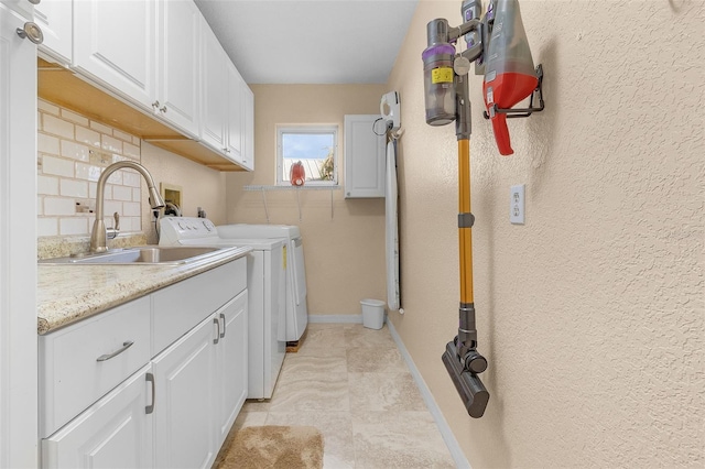 clothes washing area with cabinets, light tile patterned floors, washing machine and dryer, and sink