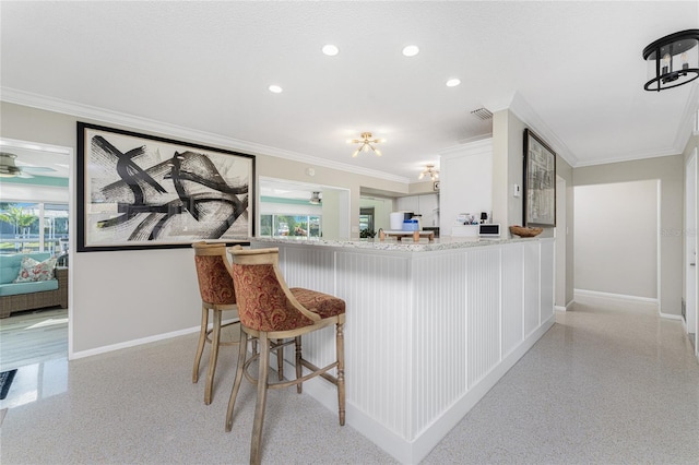 kitchen featuring white cabinets, kitchen peninsula, crown molding, and a breakfast bar area