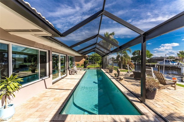 view of pool featuring a patio, a water view, and glass enclosure