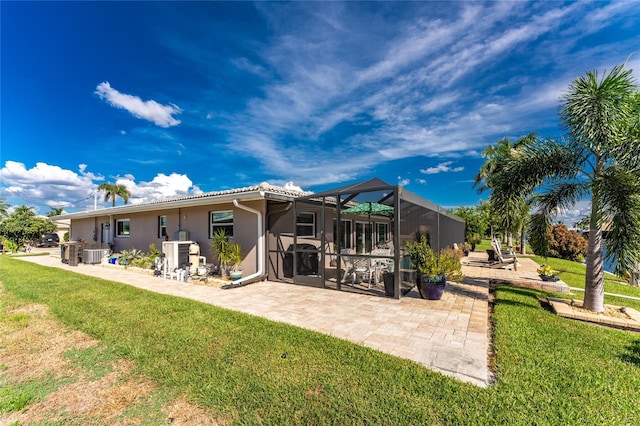 rear view of house featuring glass enclosure, a yard, a patio, and central AC unit