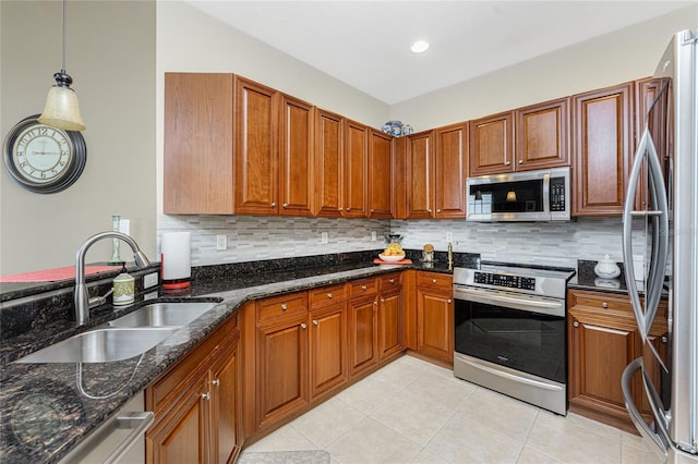 kitchen with appliances with stainless steel finishes, tasteful backsplash, sink, dark stone countertops, and hanging light fixtures