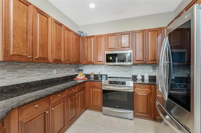 kitchen with dark stone counters, backsplash, light tile patterned flooring, and stainless steel appliances