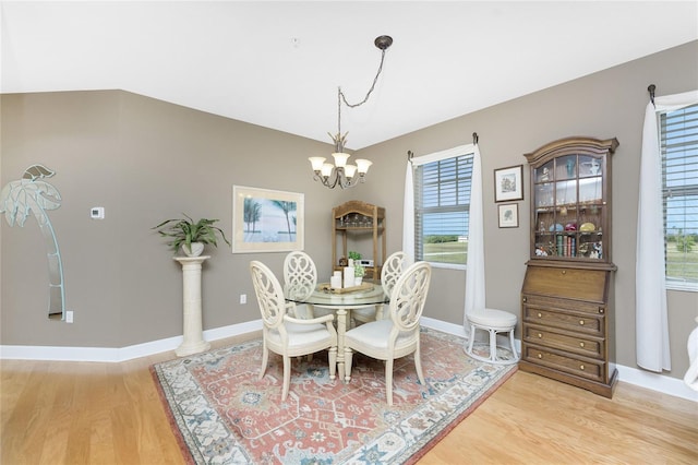 dining area with hardwood / wood-style floors, plenty of natural light, and a chandelier